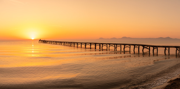 Wooden pier in the beach. Wood bridge in the beach. Sunset in the beach, golden hour. Mallorca island, 