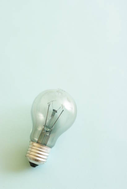 istock Traditional style glass light bulb with burnt tungsten on blue background. 1405009245