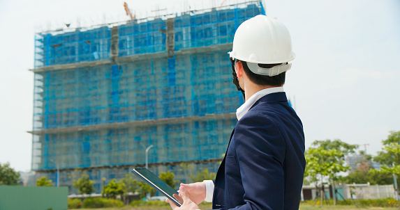 Professional architect contractor or Worker Wearing suit and Hard Hat inspects construction site by digital tablet