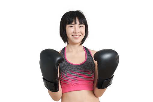 Young asian woman smiling and posing wearing boxing gloves, isolated on white background.