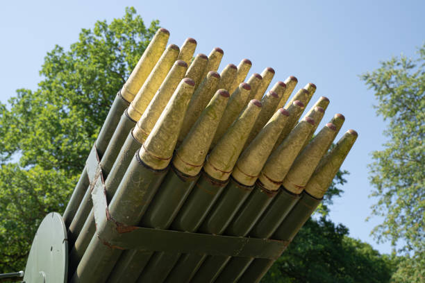 closeup of mobile auto transport with old rocket missile launching system painted green and yellow camo with sky and trees in the background