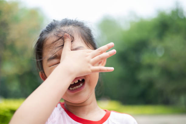 niña llorando y secándose las lágrimas con la mano - musgo apretado fotografías e imágenes de stock