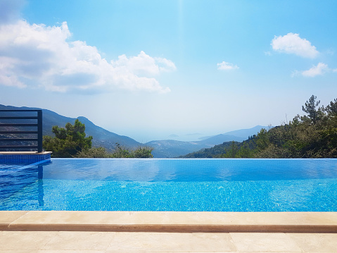 Man sits on edge of infinity pool looking out over view of Santorini caldera, Greece