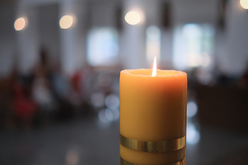 Big candle burning in a church interior.