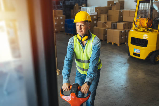 istock Man wearing hardhat and protective clothes using pallet jack 1405039379