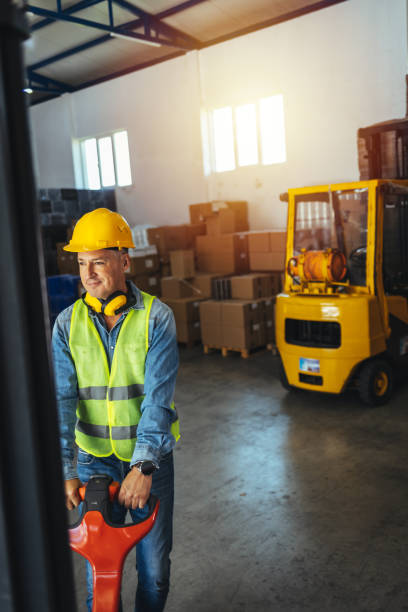 istock Worker of warehouse in uniform pulling loaded cart 1405039390