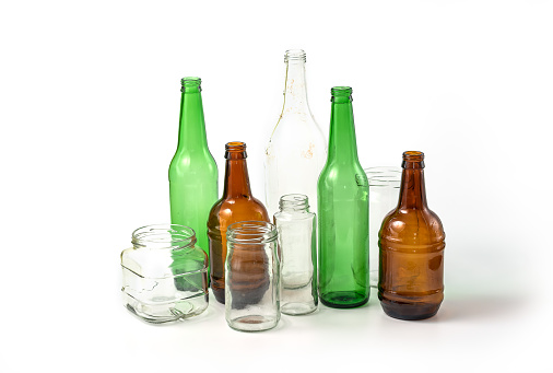 Glass ready to recycle, isolated on white background. A collection of different colored glass bottles and jars. Recycle concept.