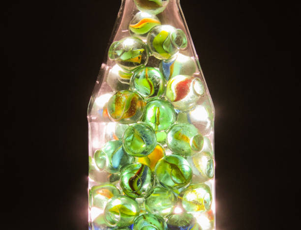 istock Close-up shot of various colored glass marbles inside a bottle with a backlight. Beautiful shiny marbles 1405039477
