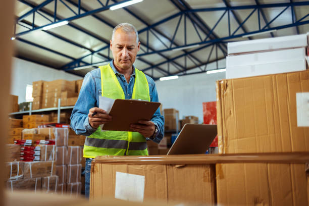 istock Warehouse manager holding a clipboard checking inventory in a large distribution center 1405039826