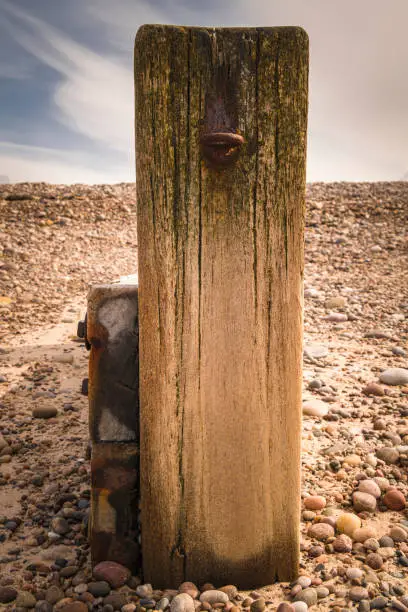 A summer portrait HDR image of a wooden breakwater endpost with an eyebolt in on Findhorn Beach, Moray, Scotland