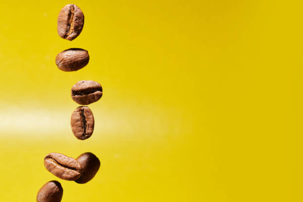 Roasted coffee beans isolated close up on yellow background, clipping path