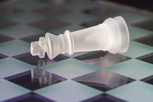 Chess with game pieces made of glass, queen, king, pawn and game board made of glass in black and white