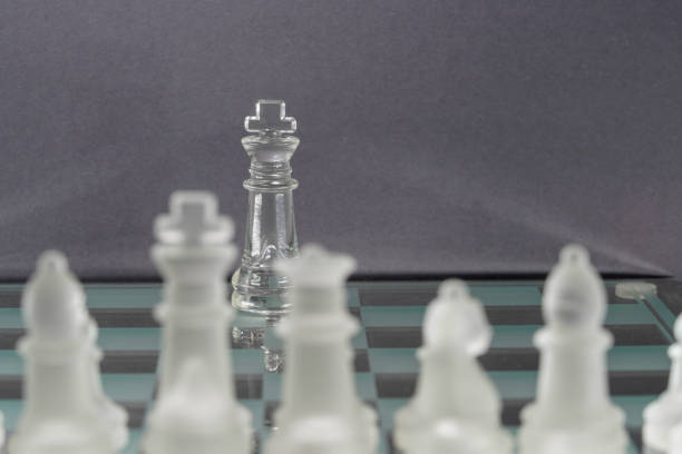 Chess with game pieces made of glass, queen, king, pawn and game board made of glass in black and white