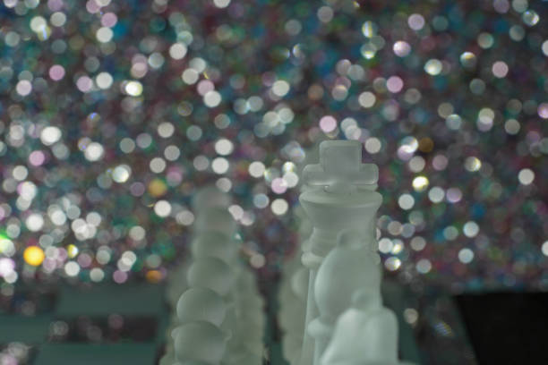 Chess with game pieces made of glass, queen, king, pawn and game board made of glass in black and white