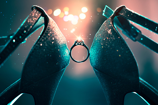 Wedding Bridal Shoes holding a Ring with color lights on the background.