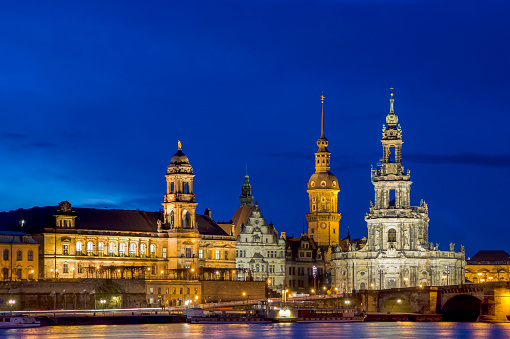 View of the old town of Dresden at night with Hofkirche, Augustusbrücke, Georgentor and the Elbe in the foreground with artificial lighting