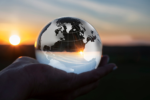 Beautiful sunset on the rocks through a crystal lens ball  on a beach