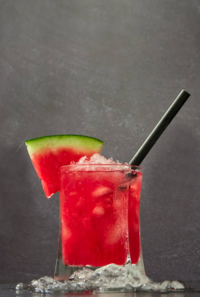 istock Red fruit cocktail Gin for spring or summer on dark blurred background. Refreshing non-alcoholic watermelon drink served in a crystal glass with ice. Copy space 1405055730