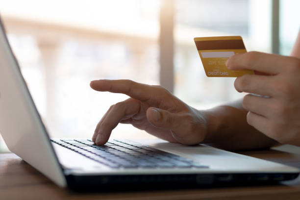 istock Businessman hand holding credit card with using laptop for online shopping while making orders at home. 1405056723