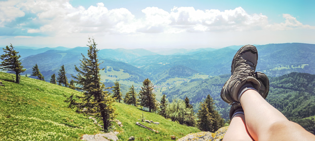 Wonderful view from Belchen hill mountain, surrounded by green fresh meadow and forest trees - Landscape Southern Black Forest Aitern Germany background panorama - Hiking, young woman is sitting on a rock and wearing walking Bootsbauer