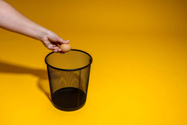 istock The hand throws a chicken egg into the trash. The egg is thrown into the office wastebasket. Poultry production problems concept 1405060127