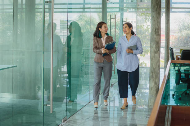 istock Asian business people colleagues working together discussing while walking at modern office corridor 1405061356