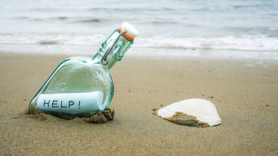Bottle on beach with message on paper inside in rainy day