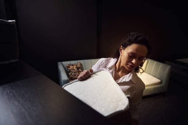 istock Hispanic multitasking woman sales manager, interior designer arranging samples of orthopedic mattresses on the stand in the showroom of a furniture design store. Healthy sleep concept 1405063432