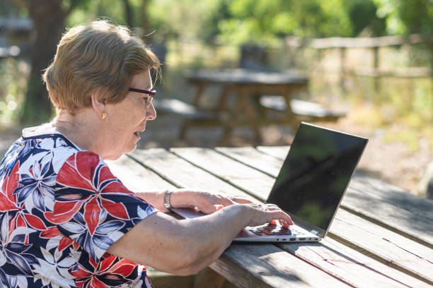 istock senior woman using laptop outdoors park 1405063799