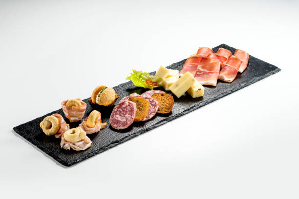 istock Black stone rectangular tray with snacks speck bacon salami taralli salted macaron cheese with jam 1405064879