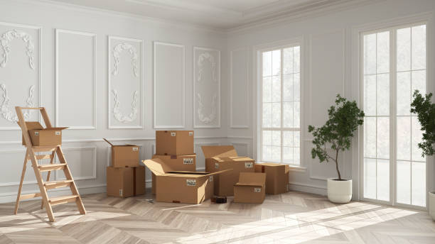 istock Cardboard carton boxes stack in classic empty room, wooden step ladder, interior design. Wall moldings and parquet floor, windows and potted plants. Moving concept idea 1405066856