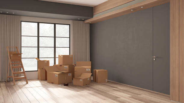 istock Cardboard carton boxes stack in modern empty room, wooden step ladder, minimalist interior design. Panoramic window, parquet floor and concrete walls. Moving concept idea 1405066882