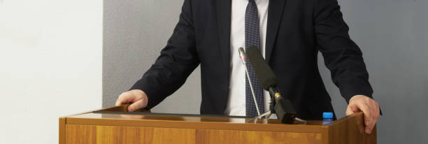 un homme - un avocat, un politicien, un homme d’affaires ou un fonctionnaire parle, appuyant ses mains sur un podium ou une chaire. déclaration officielle. orateur, conférencier ou interviewé - senator photos et images de collection