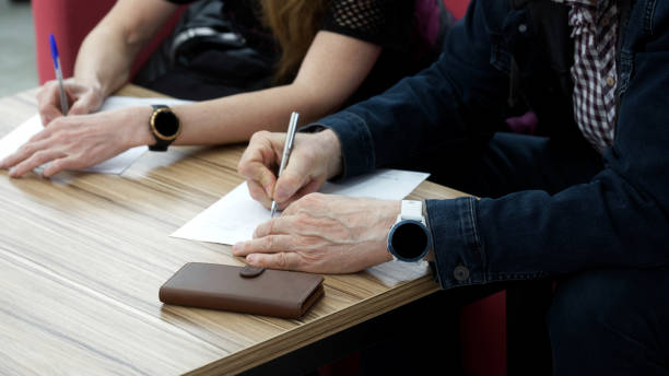 hombre y mujer adultos llenan los formularios. concepto de procedimientos de divorcio, firma de un contrato de matrimonio, contrato de arrendamiento o poder notarial. sin rostro - division fotografías e imágenes de stock