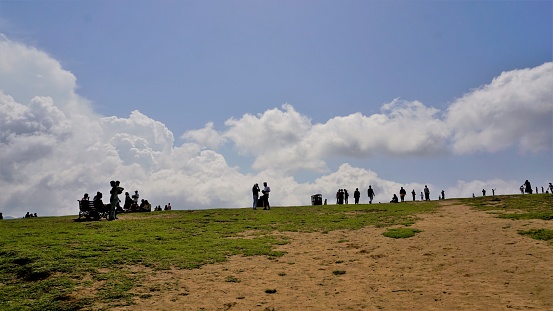 Ooty,Tamilnadu,India-June 04 2022:Tourists enjoying at the top of the beautiful green elevated lawn in ooty shooting spot popularly known as Wenlock Downs 9th Mile Shooting Point.