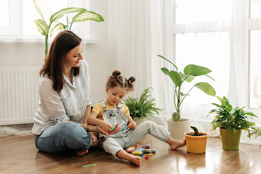 Mom and little daughter at home sculpt from plasticine and play together. The concept of preschool or home education.