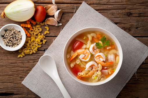 Macaroni Soup with Shrimps ,tomato ,carrots and onion on white bowl.Top view