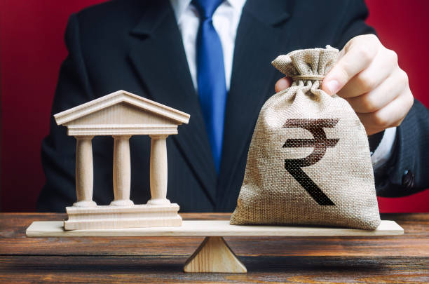 Businessman puts a indian rupee money bag on scales opposite to government building, bank, university. Lobbying interests. Taxes payment. Deposits, loans. Financial support for reforms. State debt un hombre de negocios pone una bolsa de dinero de rupia india en escalas opuestas al edificio del gobierno, el banco, la universidad. intereses de cabildeo. pago de impuestos. depósitos, préstamos. apoyo financiero a las reformas. deuda del estado