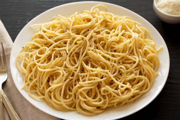 istock Homemade Cacio E Pepe Pasta with Pecorino Romano and Pepper on a white plate on a black background, side view. 1405073841