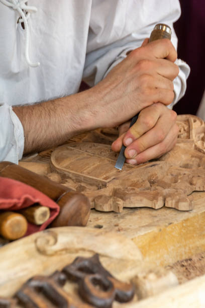 istock Carpenter craftsman carving wooden shield by hand with chisel 1405075201