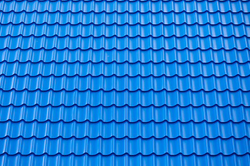 Architectural textured background of blue roof metal tile. Roof of a house with modern metal roof tiles