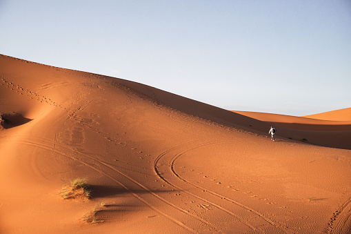 Man walking on a dune in the Merzouga desert in Morocco.