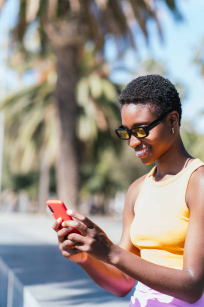 istock positive african woman using her phone outdoors on a sunny summer day 1405080199