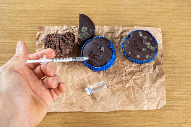 istock Man with syringe injecting insulin into moldy chocolate muffin_top view. 1405086694