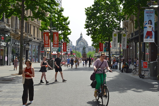 Cross walk on street Rue Montagne de la Cour in Brussels. People are walking on sidewalks, A jogger is crossing street. Some traffic is on street. Vie from square Place Royale. In background is tower of town hall at Grand Place over cityscape