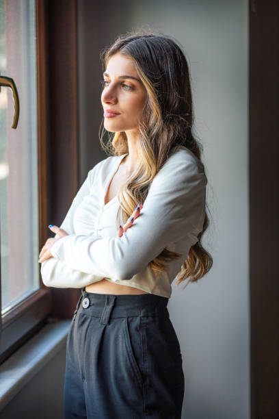 istock Young beautiful woman is standing by the window 1405088636