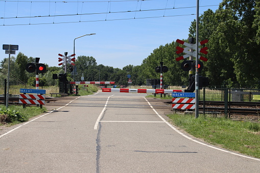 Barriers closed with red lights at railway crossing close to Dordrecht in the Netherlands