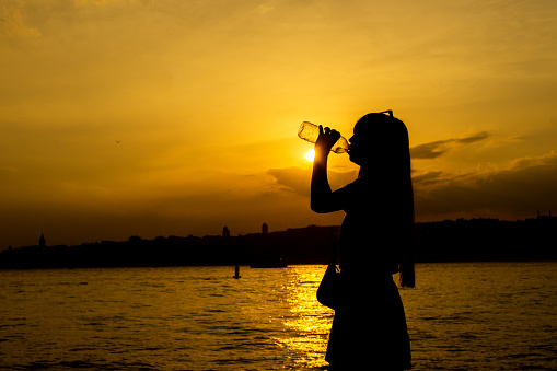 Beautiful girl drinking water at sunset