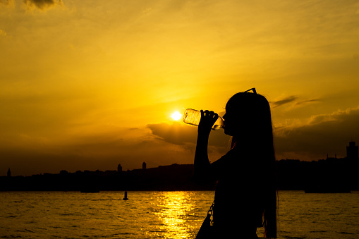 Beautiful girl drinking water at sunset