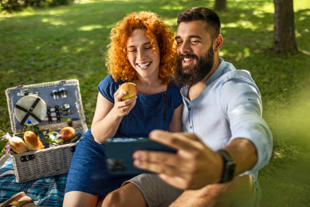 pareja romántica disfrutando de picnic haciendo selfie - wine pouring wineglass red fotografías e imágenes de stock